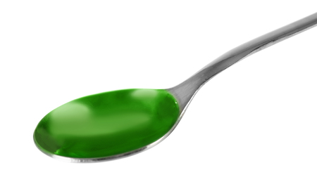 Green cough medicine syrup in silver spoon isolated on whiteの写真素材