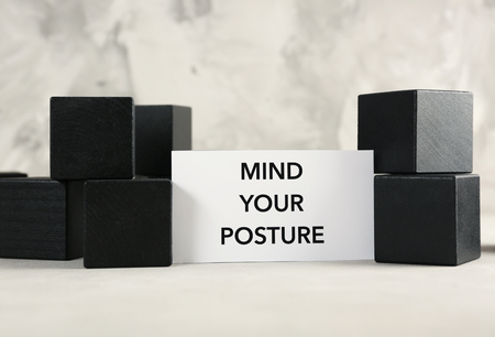Paper with phrase MIND YOUR POSTURE an black cubes on gray backgroundの写真素材