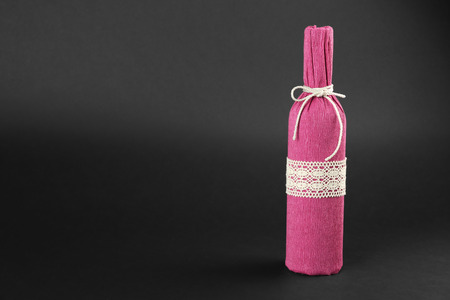 St. Valentine's Day concept. Wine bottle in gift wrap on dark backgroundの写真素材
