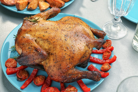 Plate with roasted beer can chicken on gray table