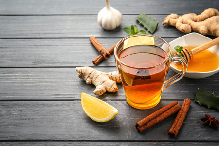 Hot drink with honey, lemon and ginger for cough remedy on wooden table