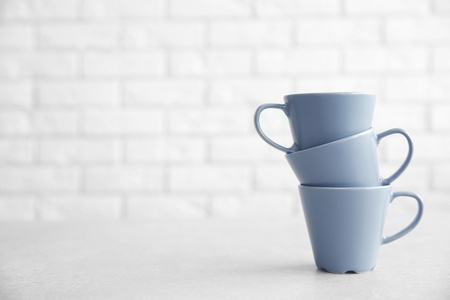 Grey cups on table against white brick wall backgroundの写真素材