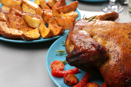 Plate with roasted beer can chicken on gray tableの写真素材