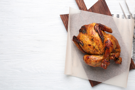 Board with roasted beer can chicken on wooden backgroundの写真素材