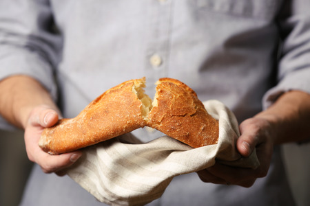 Male hands breaking freshly baked bread, closeupの写真素材