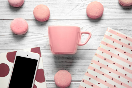 Composition with cup, macarons, phone and notebooks on white wooden backgroundの写真素材