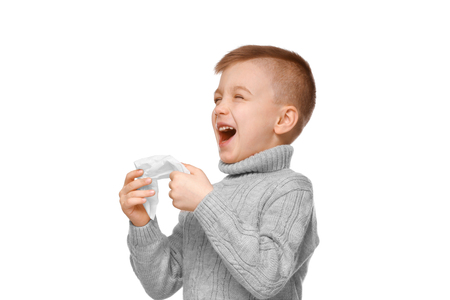 Cute little boy sneezing in tissue on white backgroundの写真素材