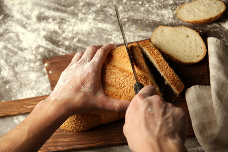 Male hands cutting wheaten bread, closeupの写真素材