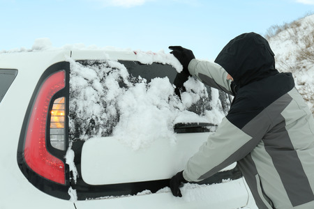 Man pushing car stuck in snow on winter roadの写真素材