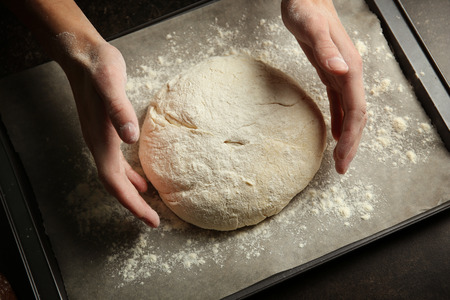 Male hands putting freshly formed loaf of bread on tray, closeupの写真素材