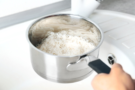 Woman rinsing rice in saucepanの写真素材