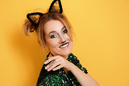 Beautiful young woman with cat makeup and ears on color backgroundの写真素材
