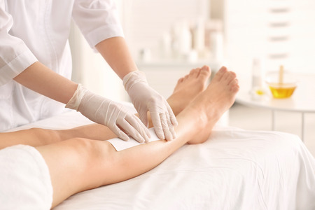 Beautician waxing female legs in spa centerの写真素材