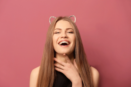 Beautiful young woman with cat ears on color backgroundの写真素材