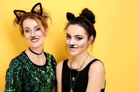 Beautiful young women with cat makeup and ears on color backgroundの写真素材