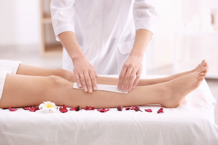 Beautician waxing female legs in spa centerの写真素材