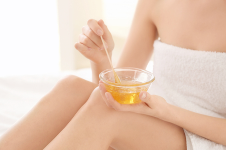 Woman holding bowl with hot wax on light backgroundの写真素材
