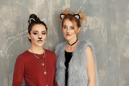 Beautiful young women with cat makeup and ears on grunge backgroundの写真素材