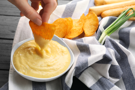Woman hand dipping nacho in beer cheese dipの写真素材