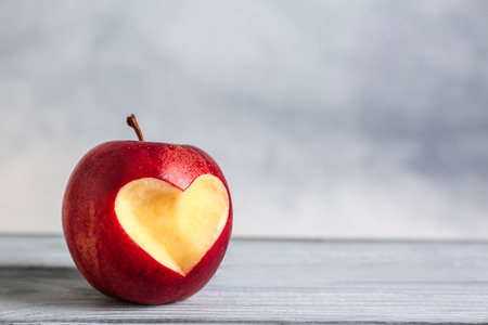 Fresh red apple with heart-shaped cut out  on wooden tableの写真素材