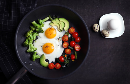 Pan with delicious roasted eggs and avocado on wooden backgroundの写真素材