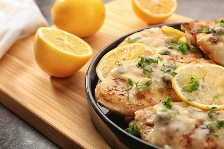 Plate with delicious chicken piccata on wooden boardの写真素材