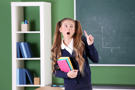 Teenage girl in school uniform standing in classroomの写真素材