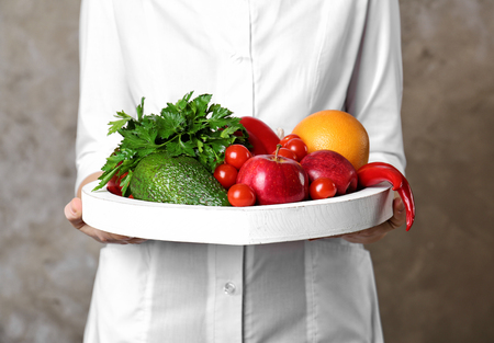 Doctor holding tray with heart healthy foods on color backgroundの写真素材