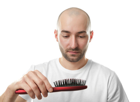 Hair loss concept. Young man with hair comb on white backgroundの写真素材