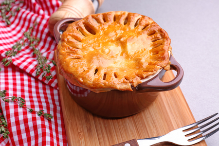 Delicious chicken pot pie in saucepan on wooden boardの写真素材