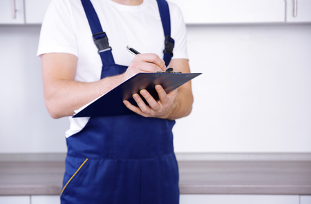 Plumber in uniform holding clipboard at kitchenの写真素材