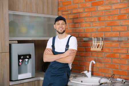 Plumber with crossed arms standing at kitchen