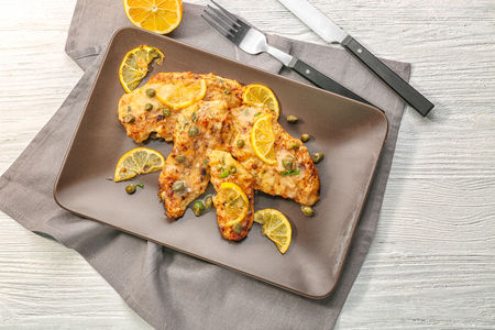 Plate with delicious chicken piccata on wooden tableの写真素材