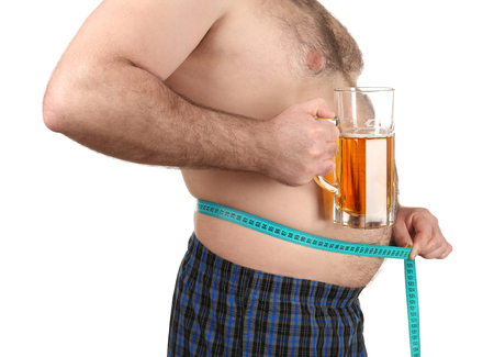 Man measuring belly and holding glass of beer on white backgroundの写真素材