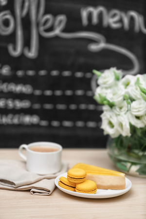 Cup of coffee, tasty cake and beautiful bouquet of flowers on table in cafeの写真素材