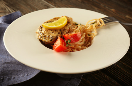 Delicious spaghetti with chicken, tomatoes and lemon on plateの写真素材