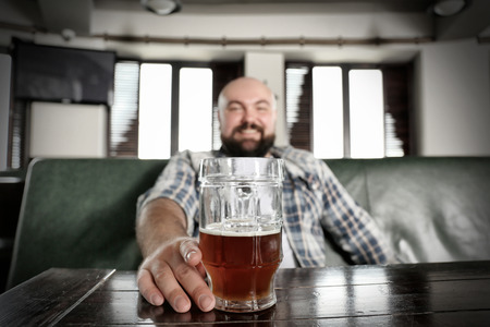 Table with glass of beer and blurred man on background