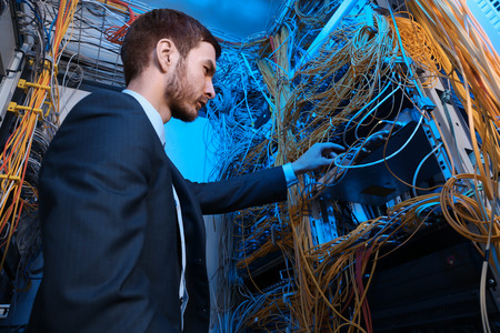 Handsome young engineer working in server room