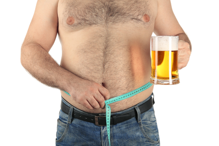 Man measuring belly and holding glass of beer on white backgroundの写真素材
