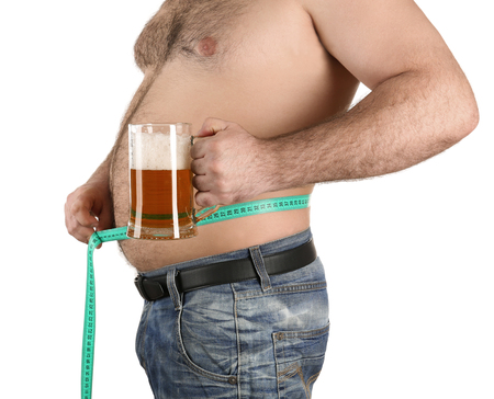 Man measuring belly and holding glass of beer on white backgroundの写真素材