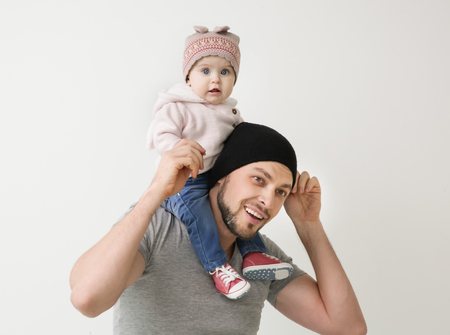 Father posing with cute baby daughter on light backgroundの写真素材