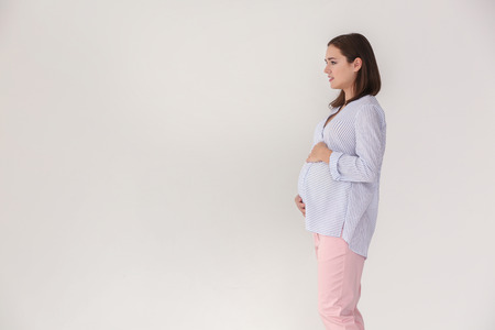 Beautiful pregnant woman on light background