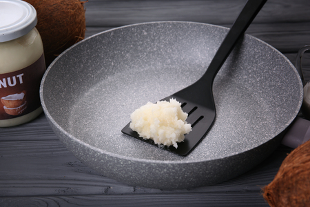Spatula with coconut oil in frying pan on kitchen tableの写真素材