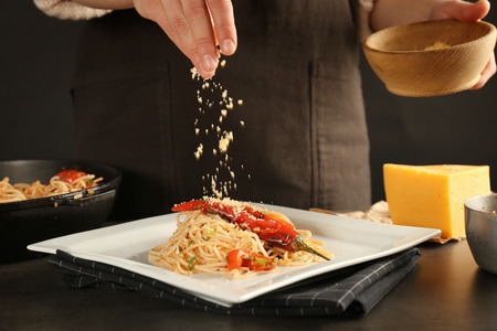 Woman sprinkling with cheese on chicken spaghettiの写真素材
