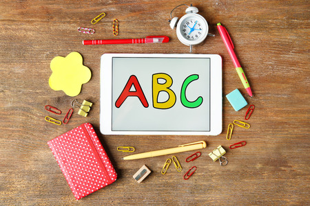 Tablet with ABC message and stationery on wooden backgroundの写真素材
