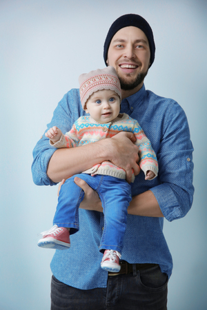 Father posing with cute baby daughter on light backgroundの写真素材