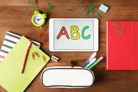 Tablet with ABC message and stationery on wooden backgroundの写真素材
