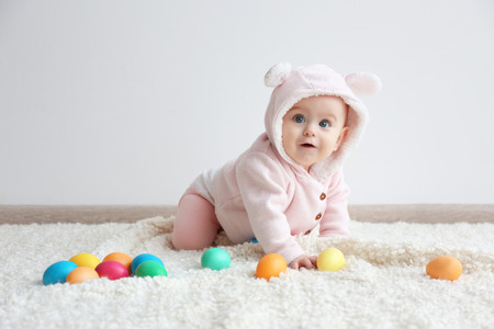 Cute funny baby with colorful Easter eggs at homeの写真素材