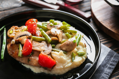 Black plate with tasty chicken marsala on tableの写真素材