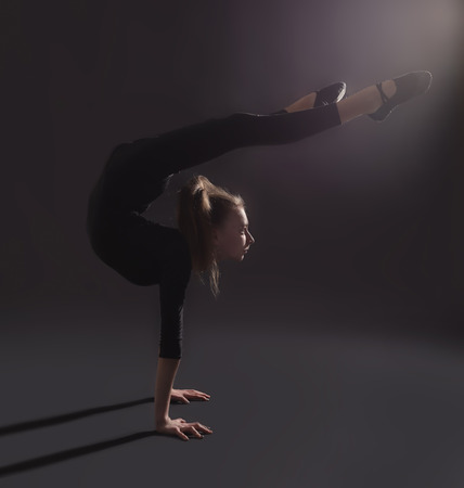 Young girl doing gymnastics on dark backgroundの写真素材